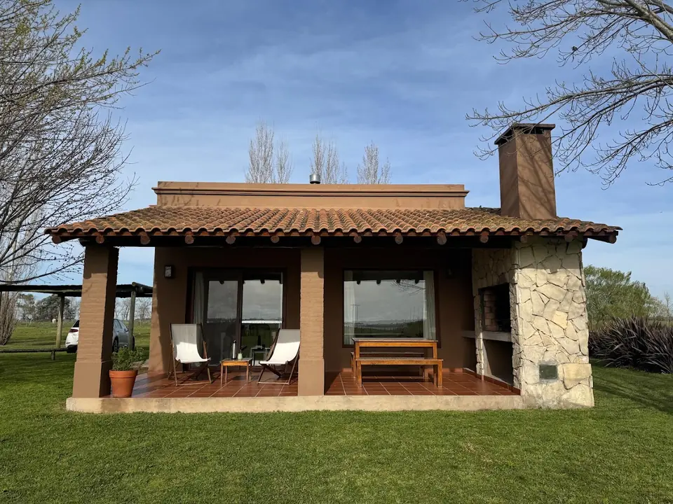 Una de las casas de techo de tejas, con la galería y la parrilla de piedra.