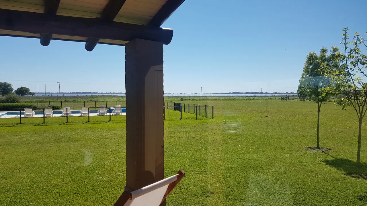 Desde la galería: una reposera, el parque, la pileta y la laguna en el horizonte.