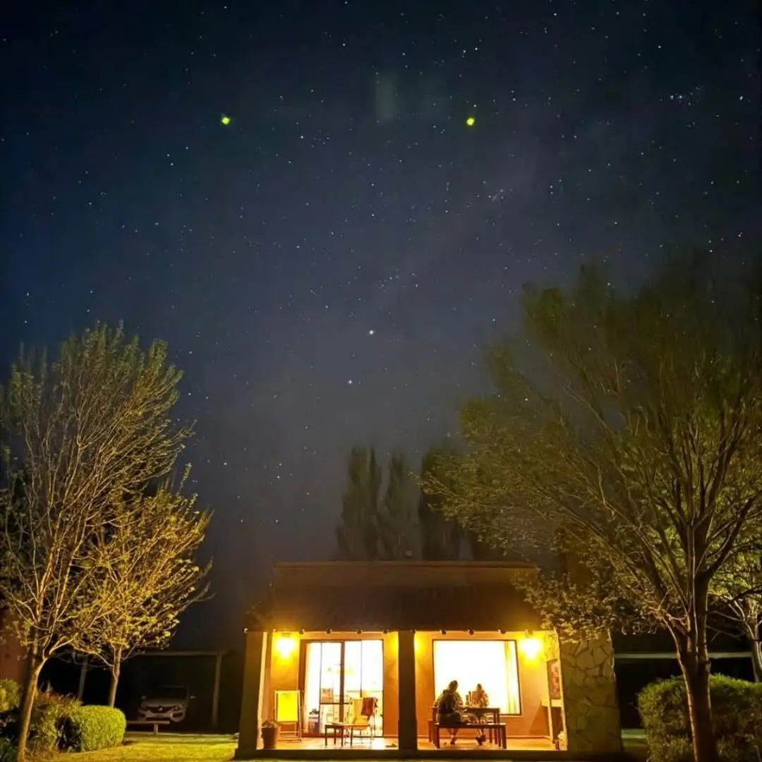 Una de las casas con las luces de la galería encendidas, bajo el cielo lleno de estrellas.